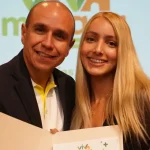 Ximena, una chica rubia y joven recibe el certificado de entrega de su nueva casa por parte de Viva mi vasa